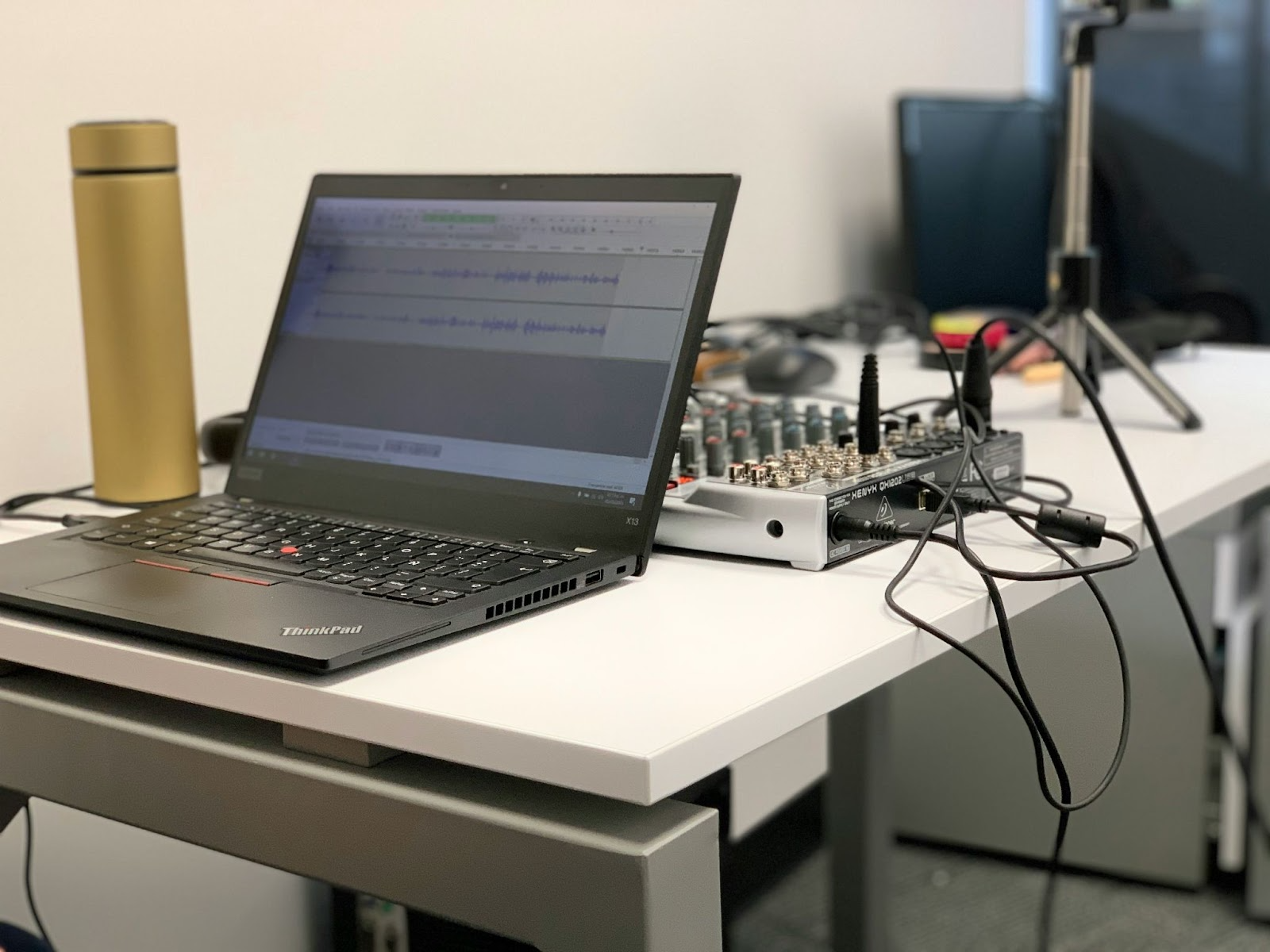 Laptop running podcast editing software next to an audio mixer